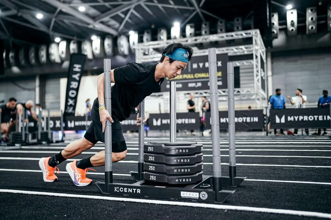 Athlete pushing a sled during an indoor HYROX event